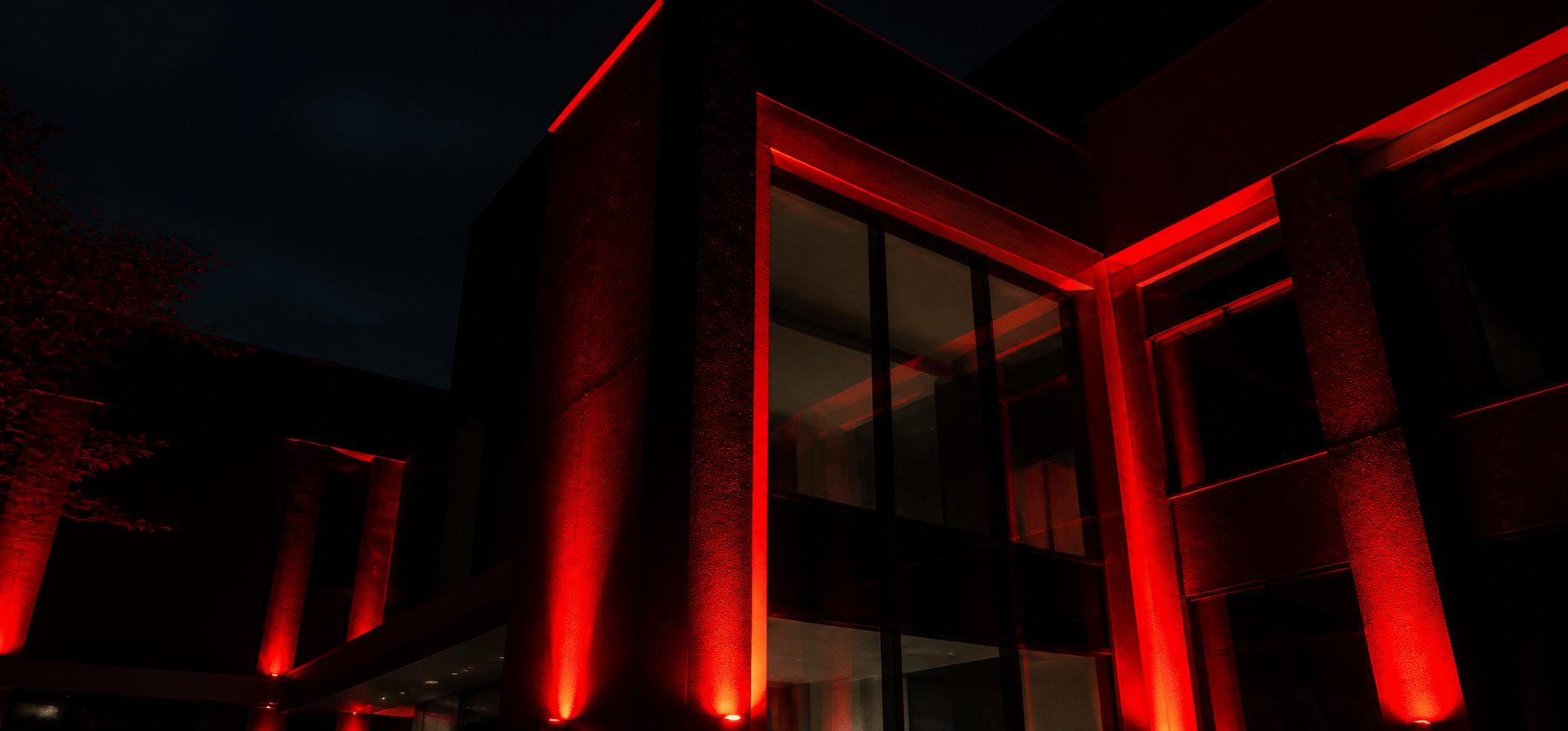 Fachada moderna con iluminación roja para representar dirección creativa y conversión