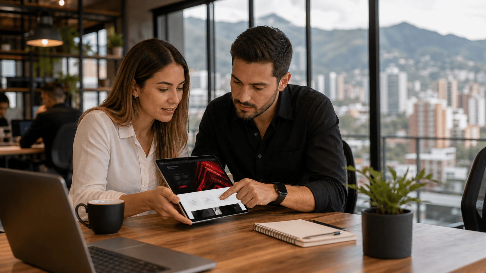 Equipo en Medellín revisando una página web en una tableta dentro de un coworking